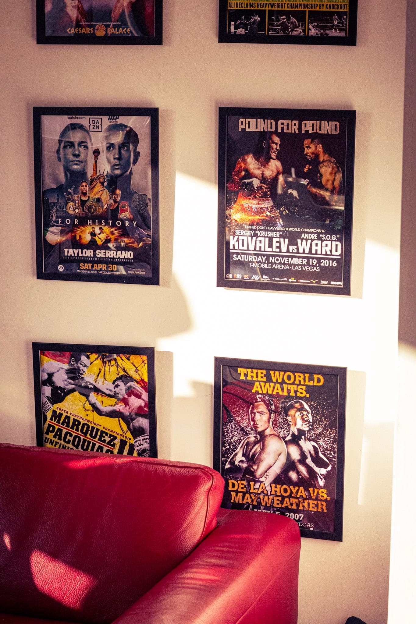 Framed fight posters above the red sofa