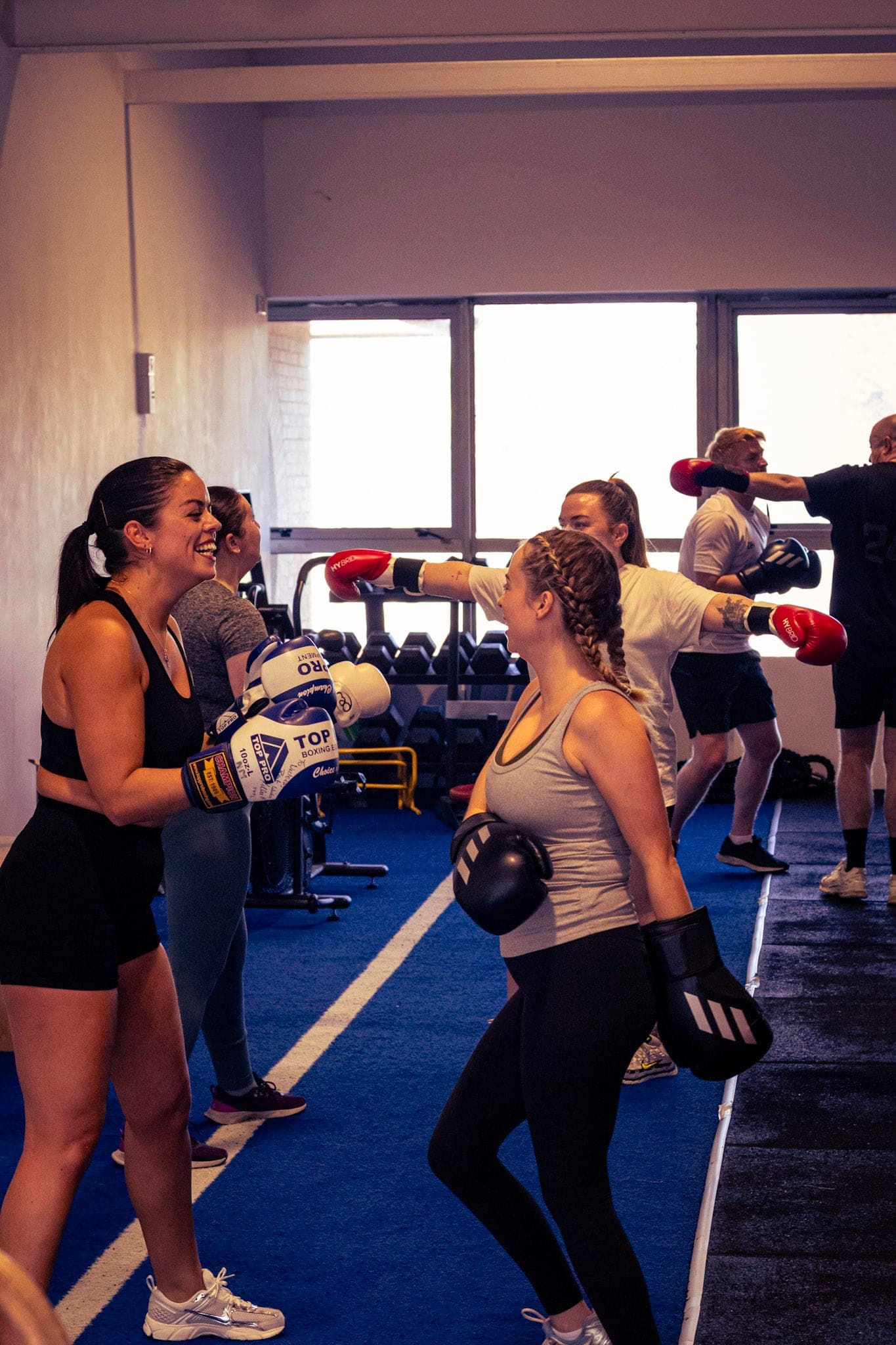 Members smiling during partner padwork in a class
