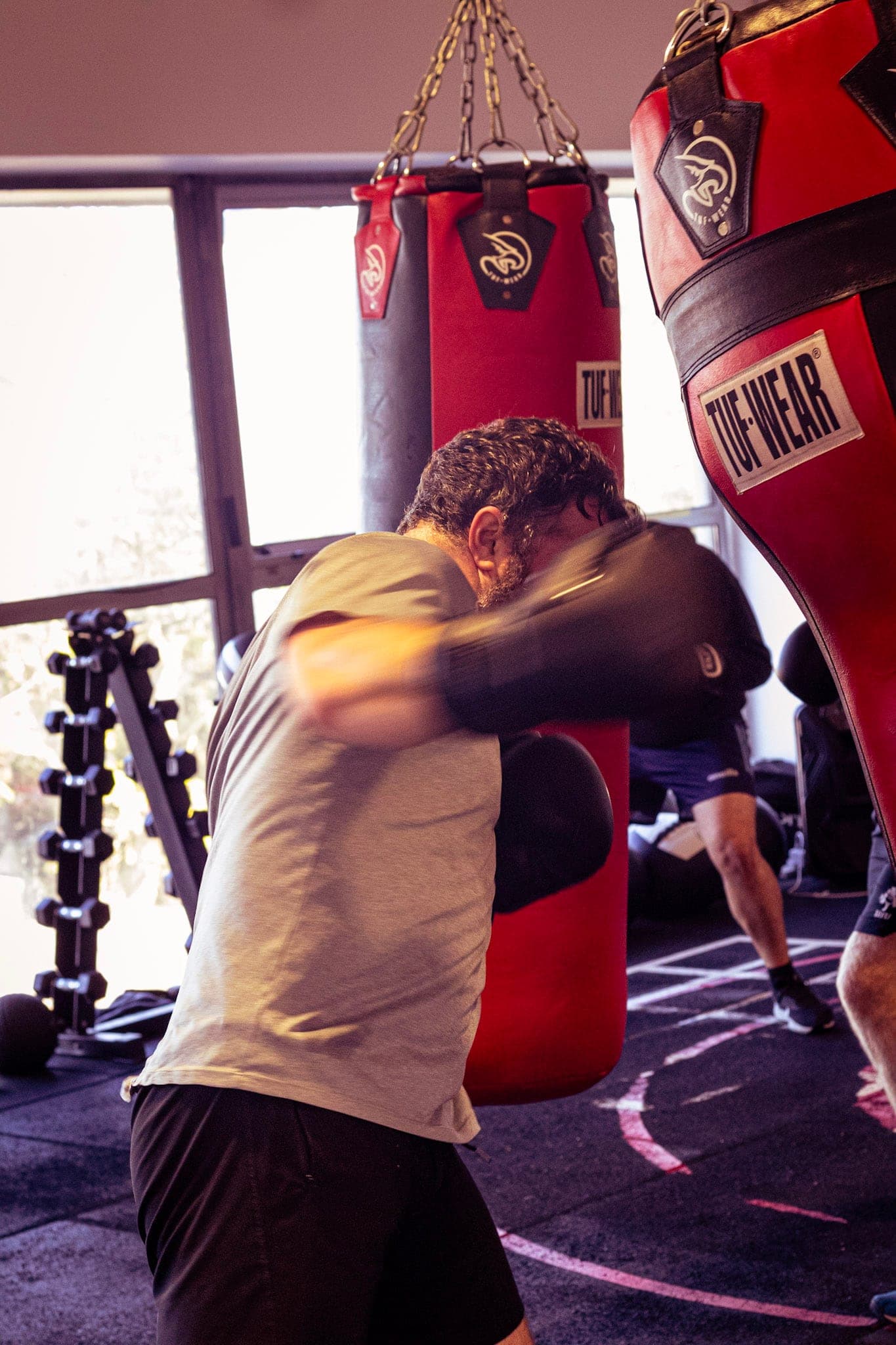 A member hitting the heavy bag beside the windows