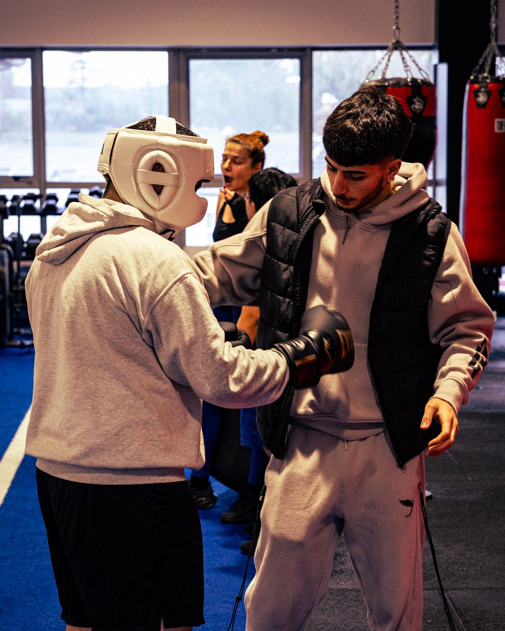 A boxer in a headguard getting gloved up to train