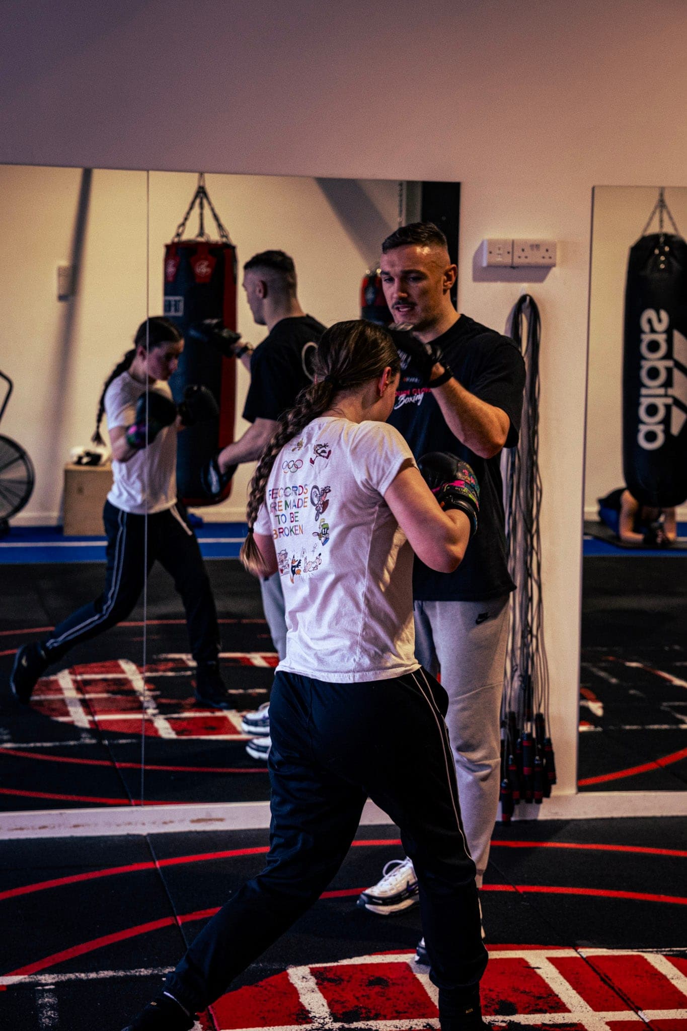 Members practising boxing with a coach watching on