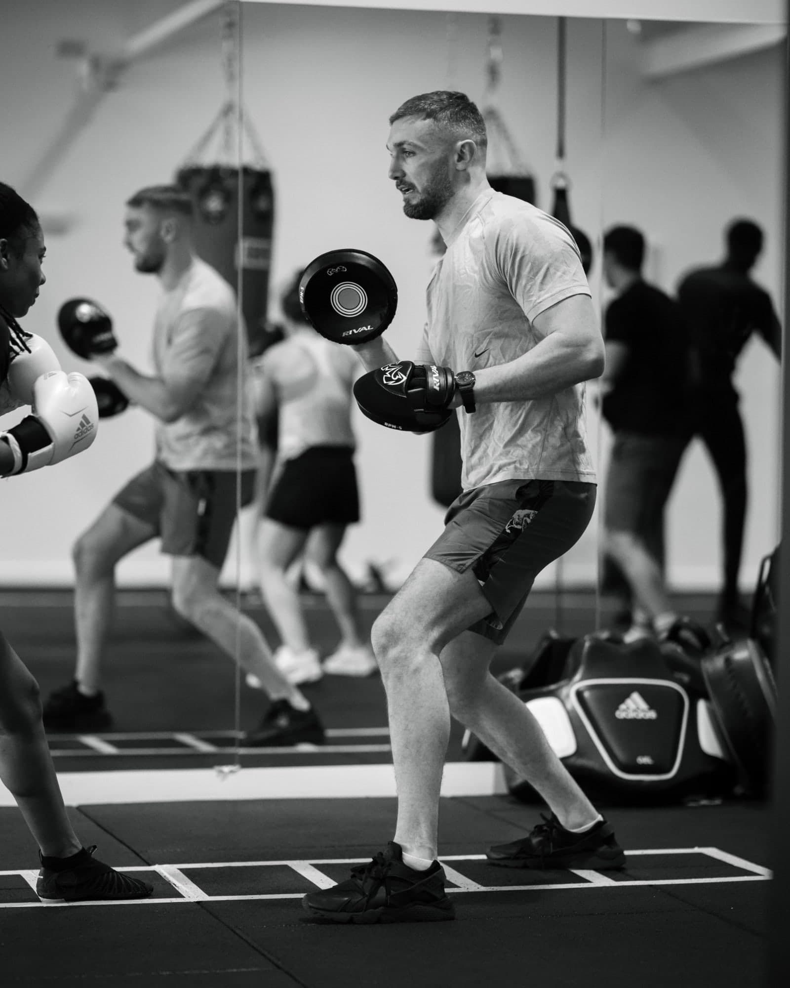 A coach holding pads for a member during a session at Tough Glove